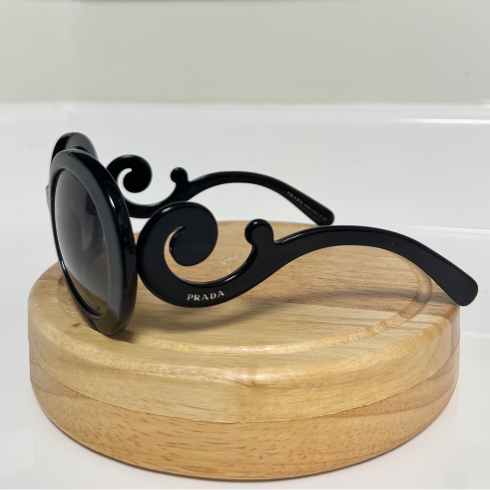 Black round Prada sunglassess with ornate arms.